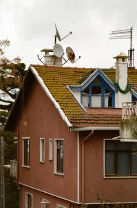 A charming rustic house with a moss-covered red roof and satellite dishes in İstanbul, Türkiye.