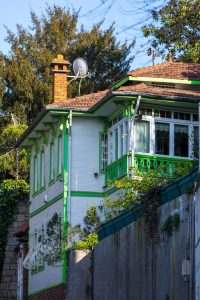 A charming house exterior with green accents and satellite dish, set against a clear sky.