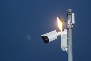 Low angle view of a security camera and light against a dark blue night sky.